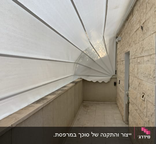 סוכך לבן מתוח מעל מרפסת אבן